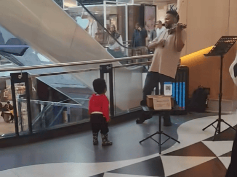A little boy dances while his father plays the violin