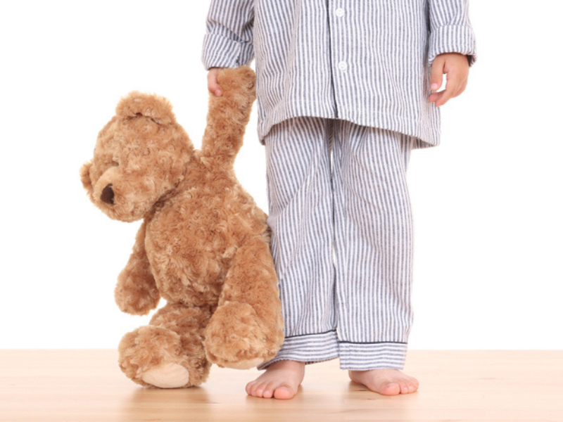 A little boy holding his teddy bear trying not to go to bed