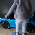 A little boy stands next to his car that needs charging