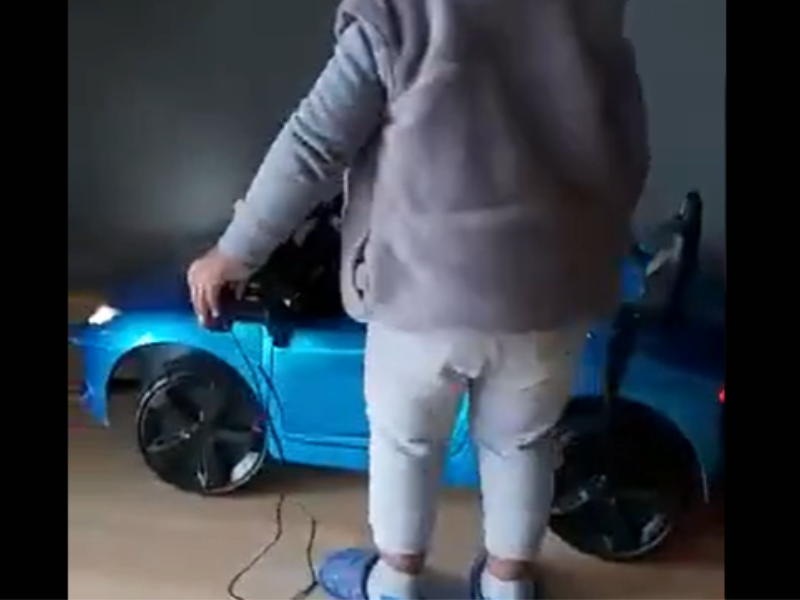 A little boy stands next to his car that needs charging