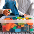 A little girl cleaning up the toy box at home