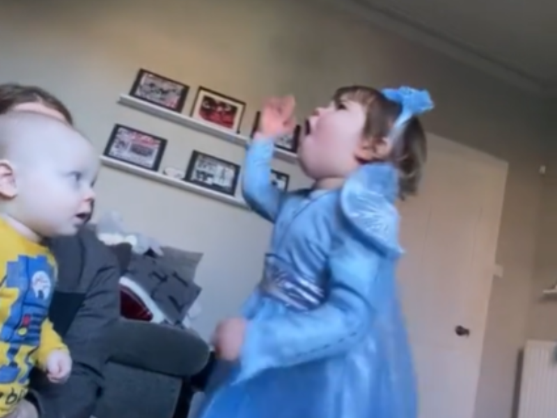 A little girl dressed like a princess is singing