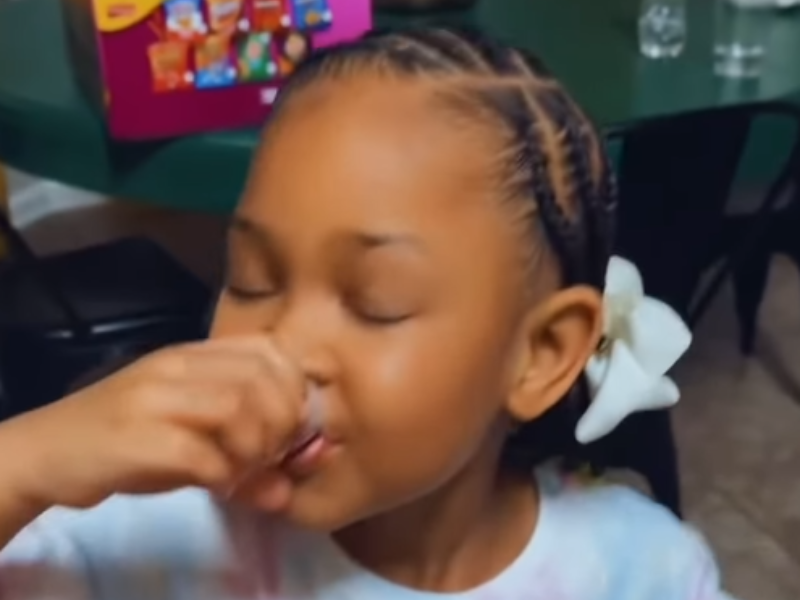 A little girl drinking medicine from a plastic cup