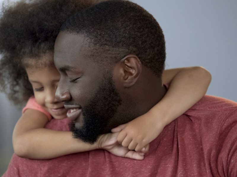 A little girl hugging her dad around his neck tightly
