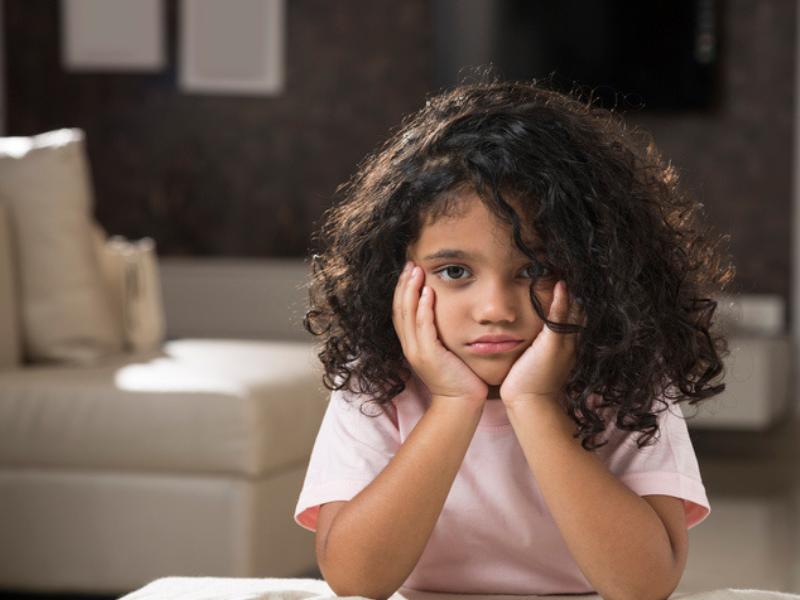 A little girl looks bored as she holds her face in her hands