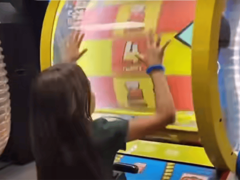 A little girl playing a game inside an arcade