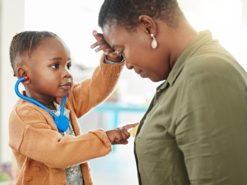 A little girl playing doctor listening to mothers heart with toy stethoscope