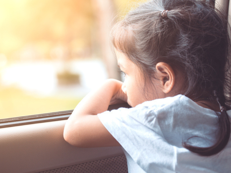 A little girl sitting in the car and looking out the window