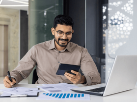 A male accountant smiles while working at his desk