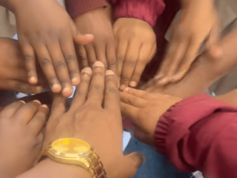 A male teacher gathers hands with his pupils