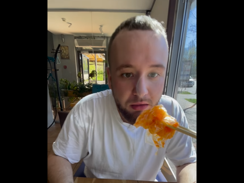 A man about to take a bite of food from chopsticks