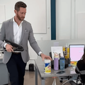 A man acts busy in the office by grabbing object off desk