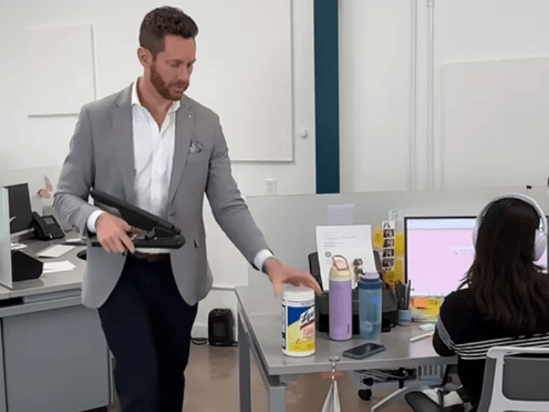 A man acts busy in the office by grabbing object off desk