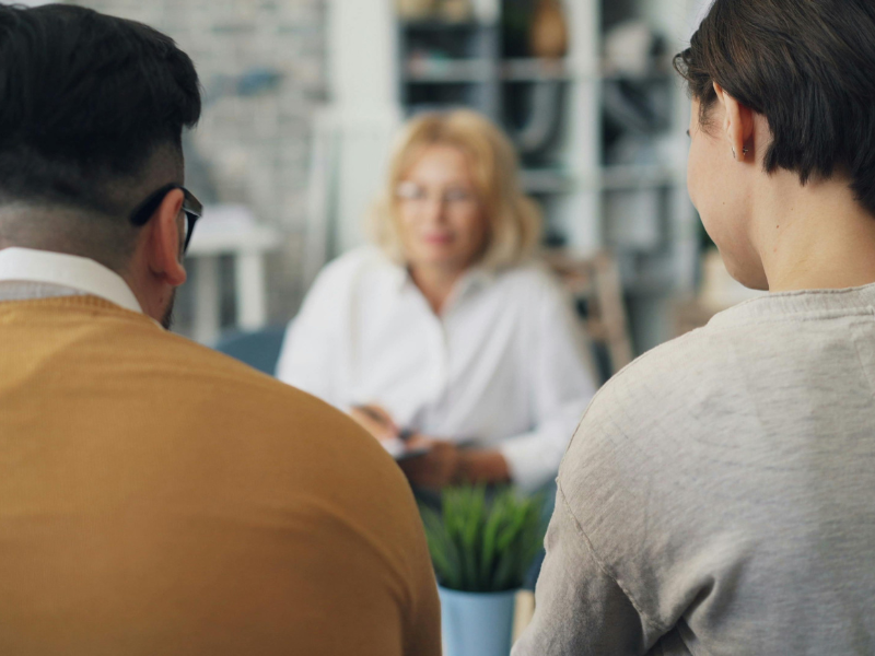 A man and woman sitting at a table talking to a coach