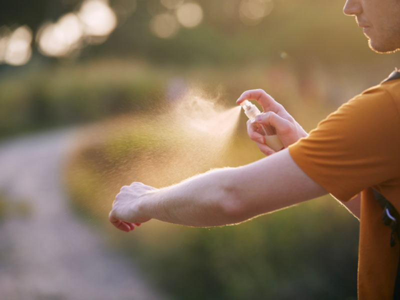 A man applying insect repellant onto his arms