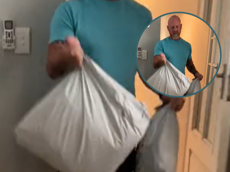 A man carrying two delivery packages into his home