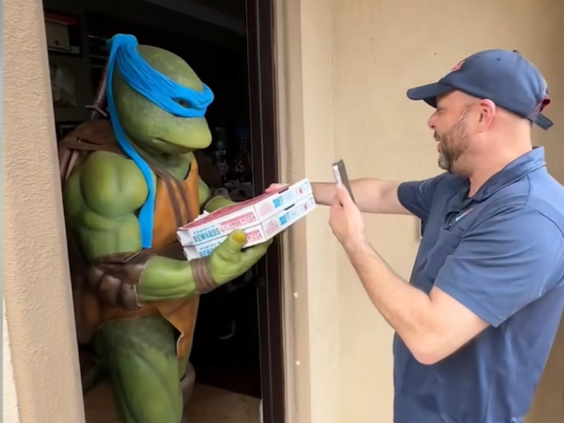 A man delivers pizza to Leonardo from the Teenage Mutant Ninja Turtles