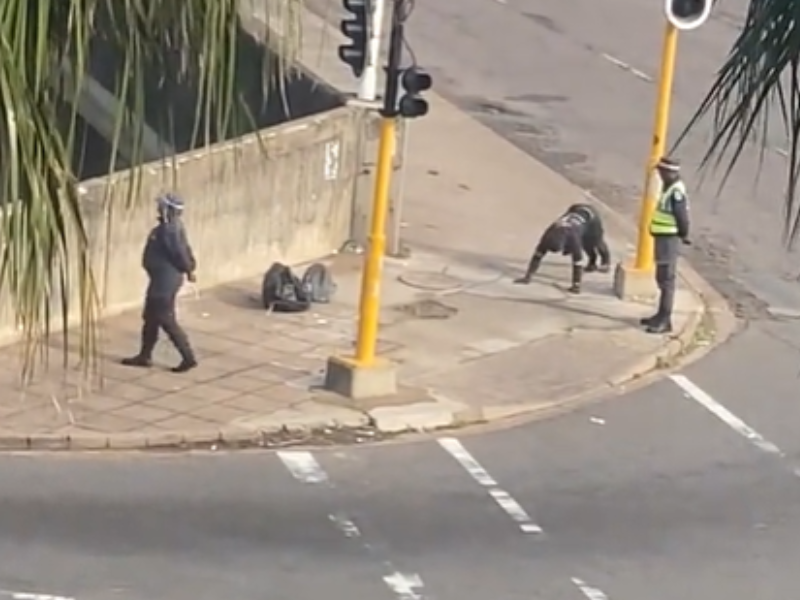 A man does push ups next to a police officer on the roadside