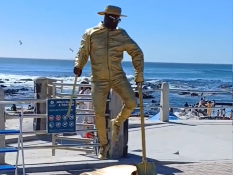 A man dressed in a gold suit levitating off the ground