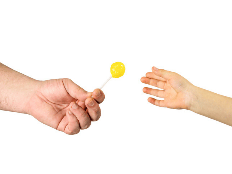 A man gives a child a yellow lollipop to lure him away