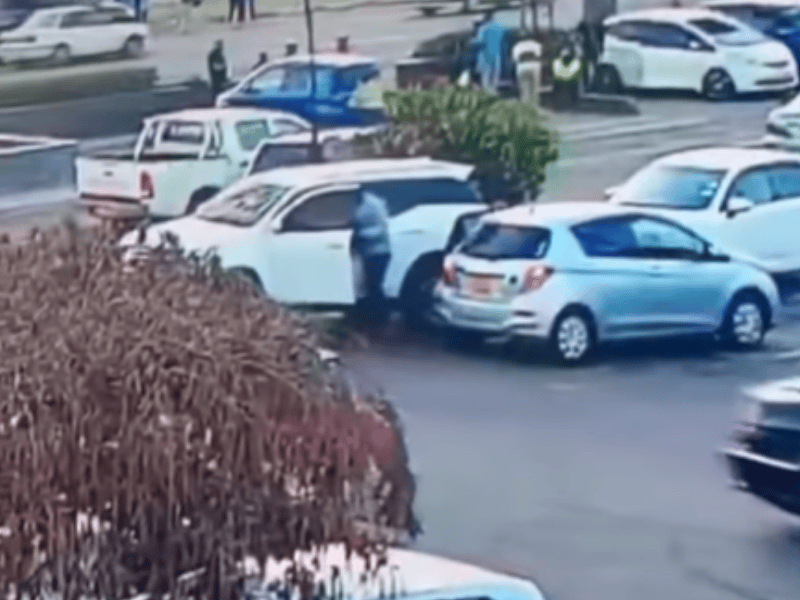 A man grabs a laptop bag from a car