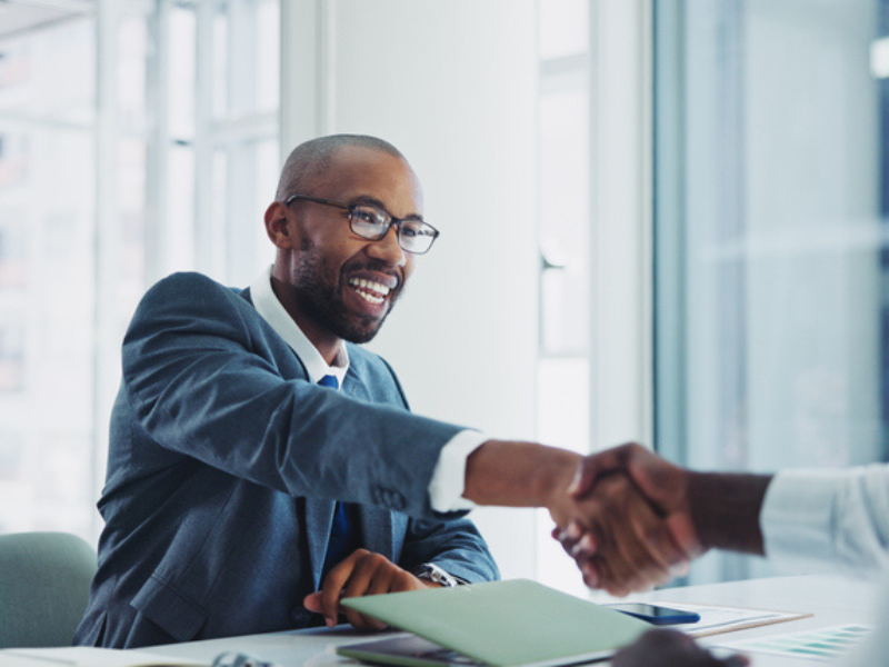 A man happily shakes hands with another person