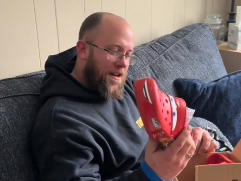 A man holds Lightening McQueen Crocs in his hands