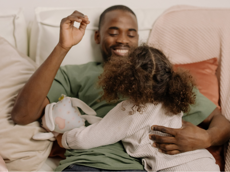 A man in green shirt playing with his daughter