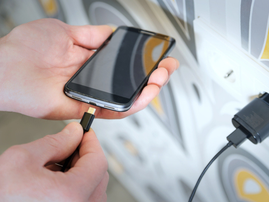 A man is plugging a charger into his smartphone