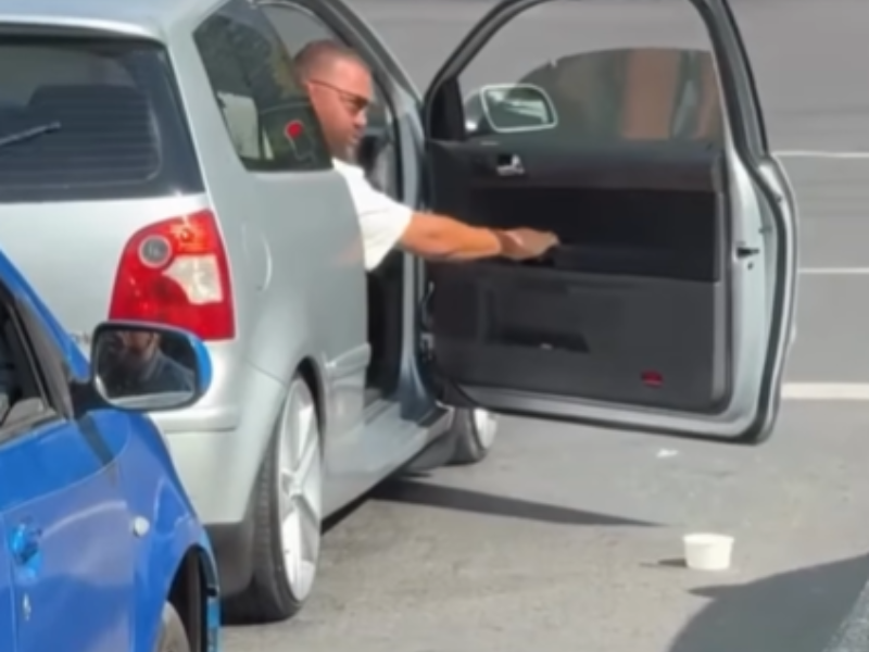 A man litters while sitting in traffic