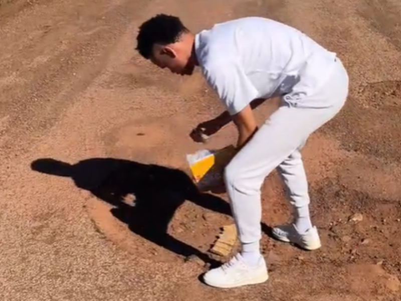 A man placing a wheat cereal inside a pothole
