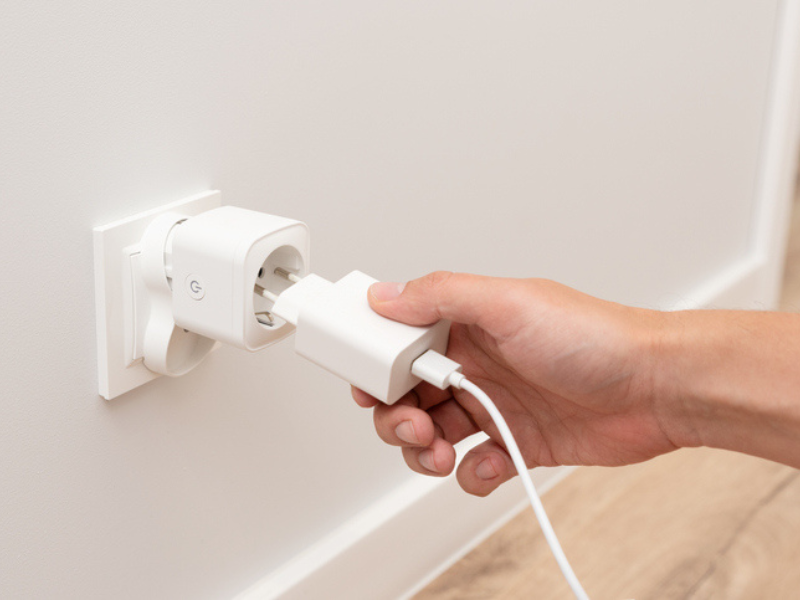 A man plugs in a charger into a smart socket