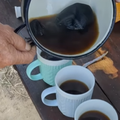 A man pours freshly brewed coffee from a pot into cups
