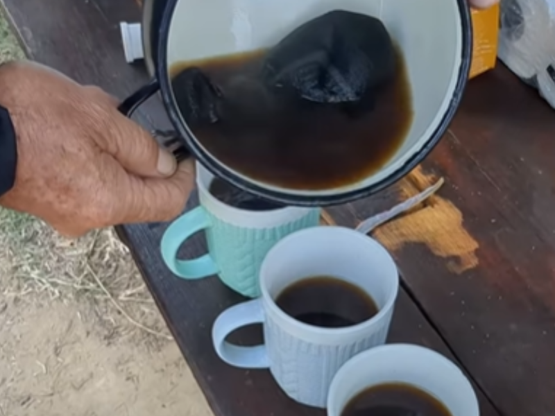 A man pours freshly brewed coffee from a pot into cups