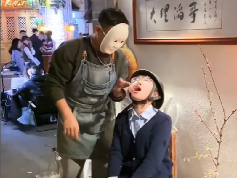 A man pours ingredients of a cocktail into a woman's mouth