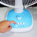 A man presses a button on the fan to turn it off