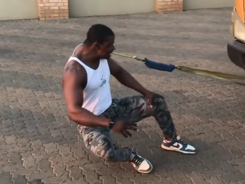 A man pulls a truck using his teeth