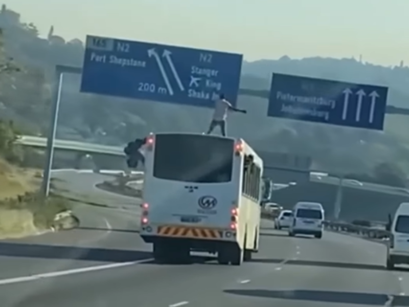 A man standing on the top of a moving bus on the N3