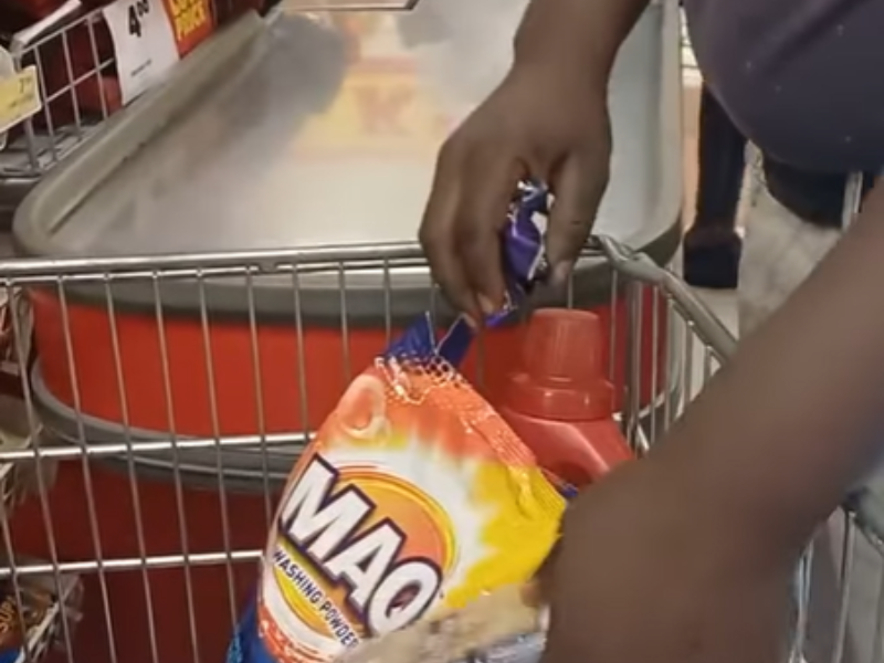 A man stands at a cashier inside Shoprite waiting to pay for his groceries