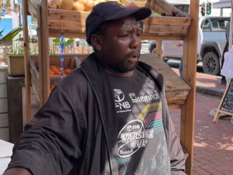 A man stands at the front of a roadside vegetable stand