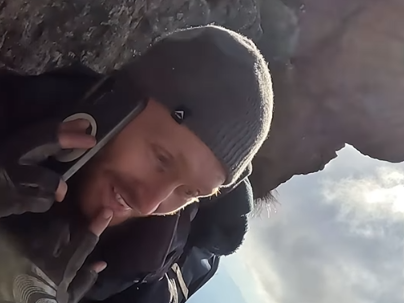 A man talking on the phone during a mountain climb