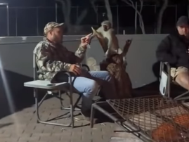 A man sitting outside at night with a monkey