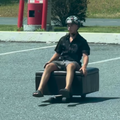 A man travelling on a motorised ottoman couch in a public space