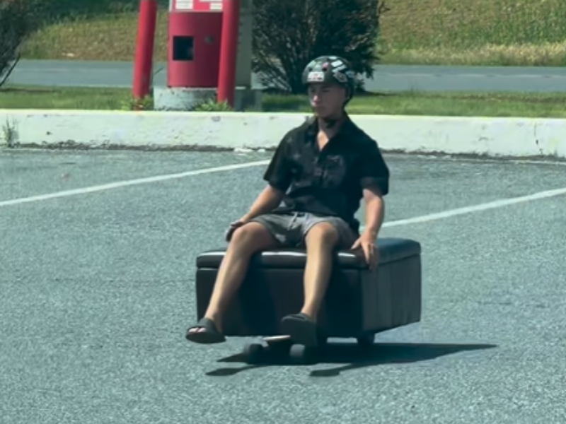 A man travelling on a motorised ottoman couch in a public space