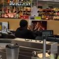 A man tries to warm his hands in front of a screen playing a fireplace video