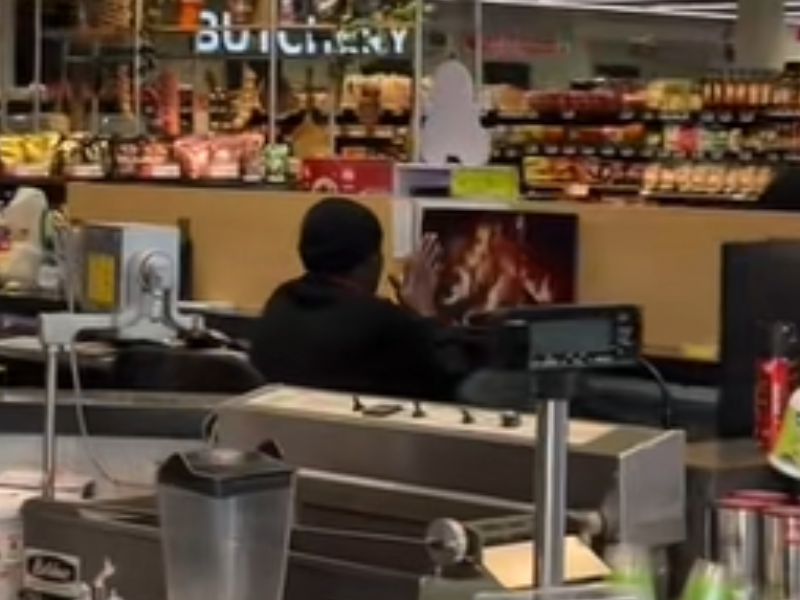 A man tries to warm his hands in front of a screen playing a fireplace video