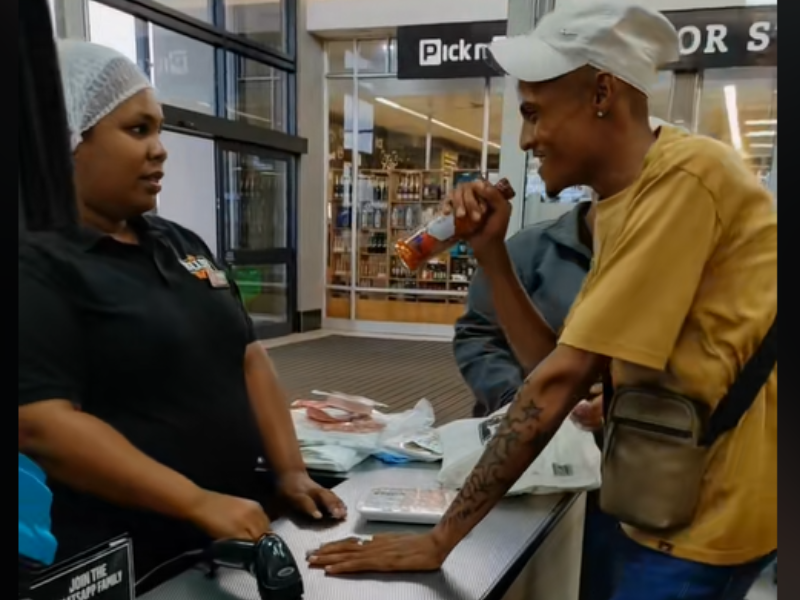 A man uses a hot sauce bottle as a mic and sings for a cashier at the checkout