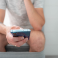 A man uses his smartphone while seated on the toilet