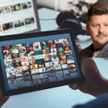 A man watching entertainment on his digital tablet with Danny Guselli image