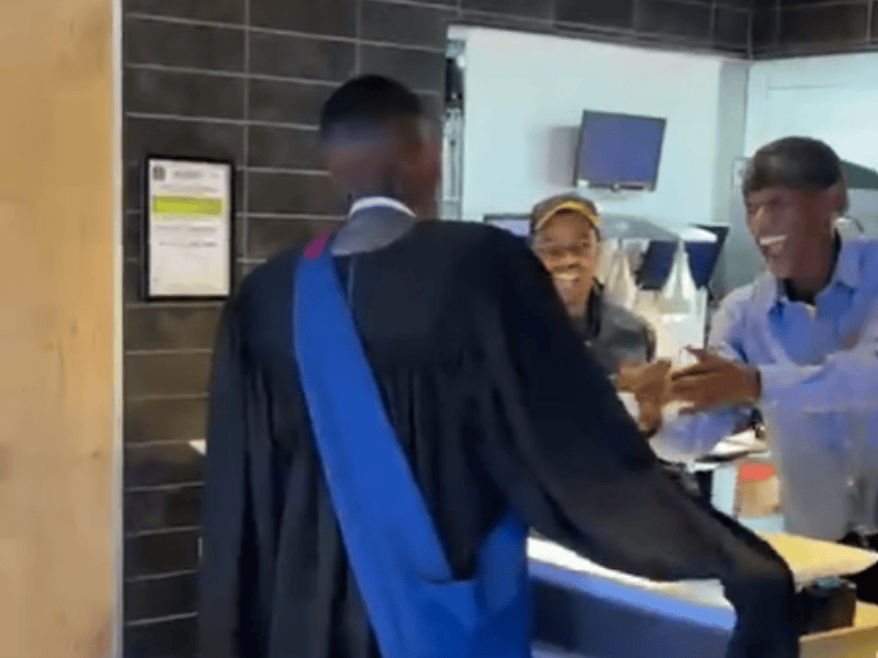 A man wearing a graduation gown celebrating with workers at Mcdonalds